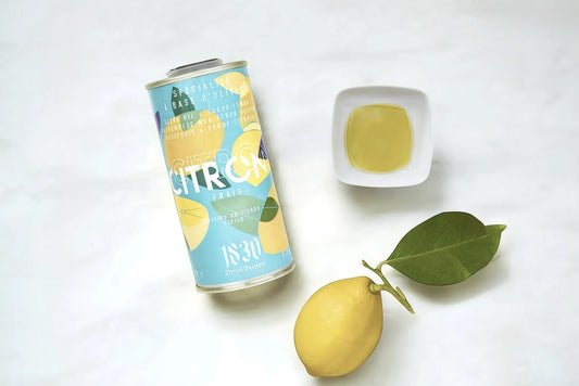 Hochwertiges Olivenöl mit Zitrone in einem stilvollen Kanister, begleitet von einer frischen Zitrone, einem Zitronenblatt und einer Schale mit goldgelbem Öl. Perfekt für mediterrane Gerichte und erfrischende Aromen.