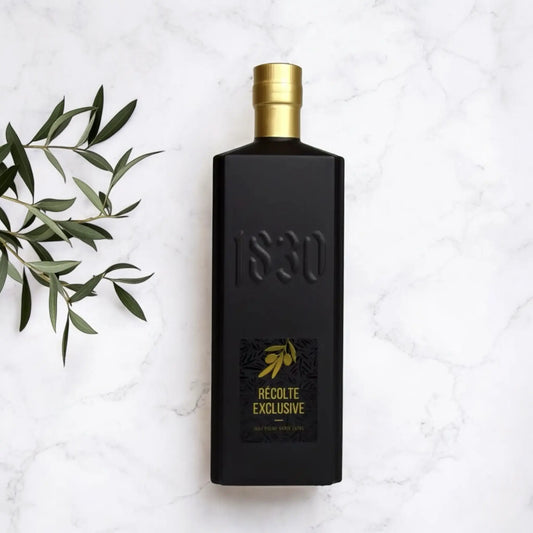 Maison Brémond Récolte Exclusive – stilvoll fotografierte Flasche Bio Olivenöl aus Frankreich mit goldener Kappe auf Marmorplatte und Olivenzweig