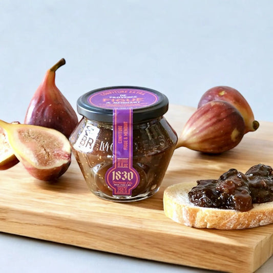 Feigenkonfitüre im Glas von 1830, umgeben von frischen Feigen und einem mit Konfitüre bestrichenen Brot – ein Genuss für Feinschmecker.