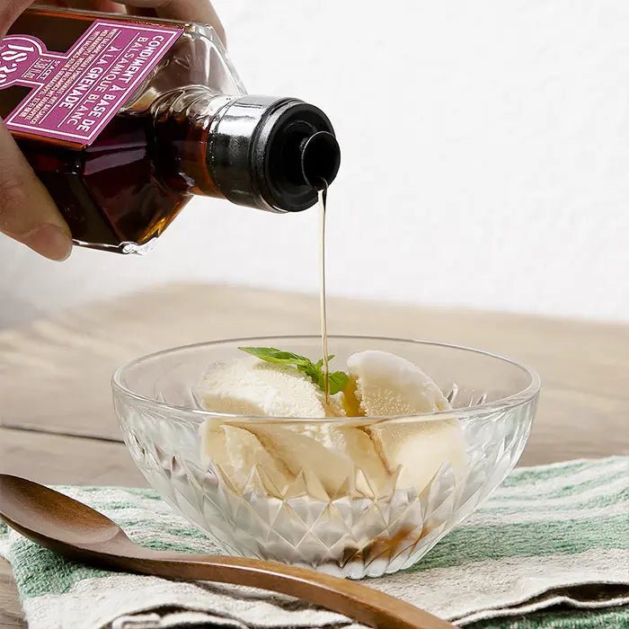 Granatapfel Weißer Balsamico Essig Condiment wird über eine Schale Vanilleeis gegossen – eine edle Kombination für besonderen Genuss.