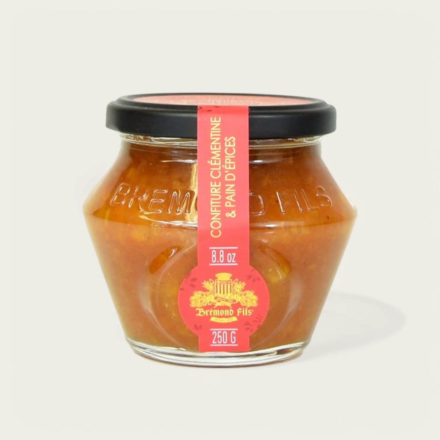 Glas mit Clementinen- und Lebkuchen-Konfitüre von "Brémond Fils", 250 g. Das sechseckige Glas hat einen schwarzen Deckel und ein rotes Etikett mit goldener Verzierung, auf dem der Produktname und die Gewichtsangabe zu sehen sind. Der Inhalt ist eine gold-orangefarbene Marmelade mit sichtbaren Fruchtstückchen.
