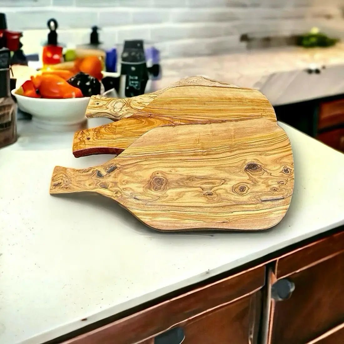 Schneidebrett aus Olivenholz mit natürlicher Maserung und Handgriff, auf weißem Hintergrund platziert.