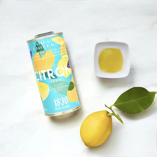 Design-Dose Olivenöl mit frischer Zitrone von Maison Brémond 1830, eine ganze Zitrone mit Blatt und eine weiße Schale mit Olivenöl auf hellem Hintergrund. Hochwertiges extra natives Olivenöl, ideal für Salate, Fischgerichte und mediterrane Speisen. Jetzt kaufen.