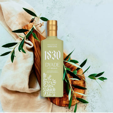 Maison Brémond 1830 Dyade Olivenöl 2. Ernte – elegante Präsentation auf Holzuntergrund mit Olivenzweig