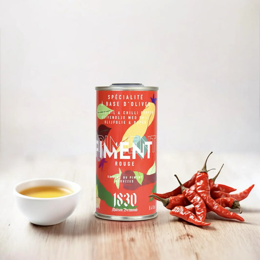 Maison Brémond Olivenöl mit Chili und frischen Schoten – Hochwertiges, würziges Olivenöl neben roten Chilischoten und einer Schale Olivenöl auf weißem Hintergrund.