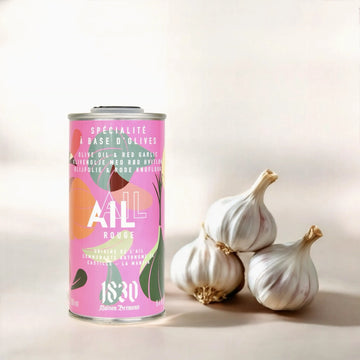 Maison Brémond Knoblauch-Olivenöl 250 ml – Aromatisches Olivenöl mit rotem Knoblauch, präsentiert neben frischen Knoblauchknollen auf hellem Hintergrund.
