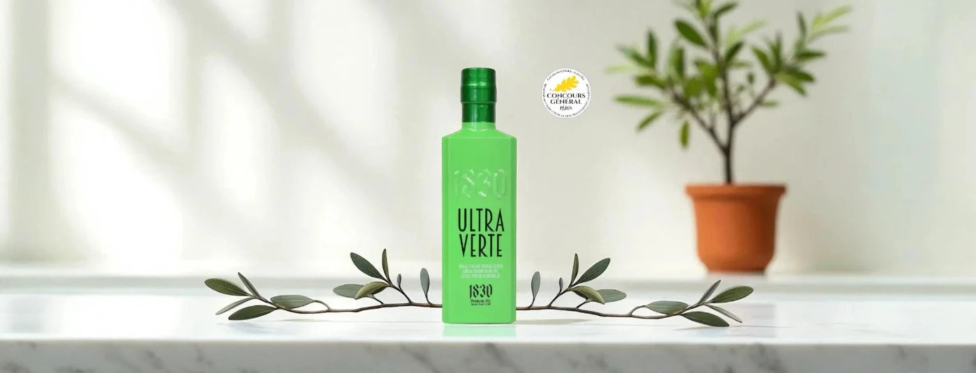 Testsieger Olivenöl kaufen aus Frankreich – hochwertiges Olivenöl auf Marmor-Tisch mit Olivenzweig, ausgezeichnet im Olivenöltest 2025