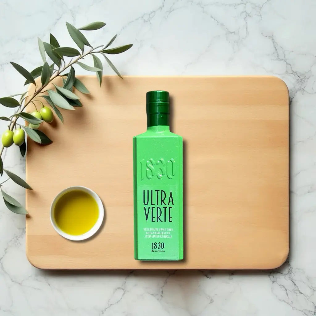 Ultra Verte Bio-Olivenöl aus Spanien – exklusive grüne Flasche mit hochwertigem extra nativem Olivenöl, platziert auf einer Marmorplatte mit Olivenzweig und Schale Olivenöl.