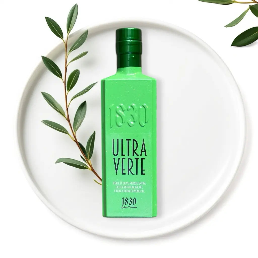 Bio-Olivenöl aus Spanien – Ultra Verte in edler grüner Flasche, stilvoll inszeniert mit Olivenzweigen und hochwertigem Design.