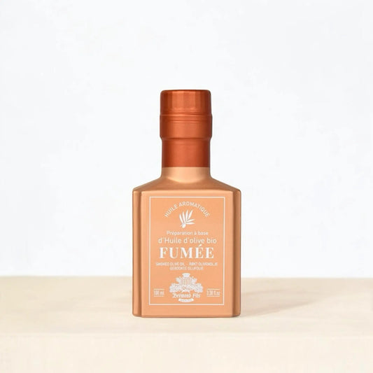 Flasche mit rauchigem Bio-Olivenöl der Marke 'Deromé Fils' in elegantem bronzefarbenem Design, auf hellem Hintergrund präsentiert.