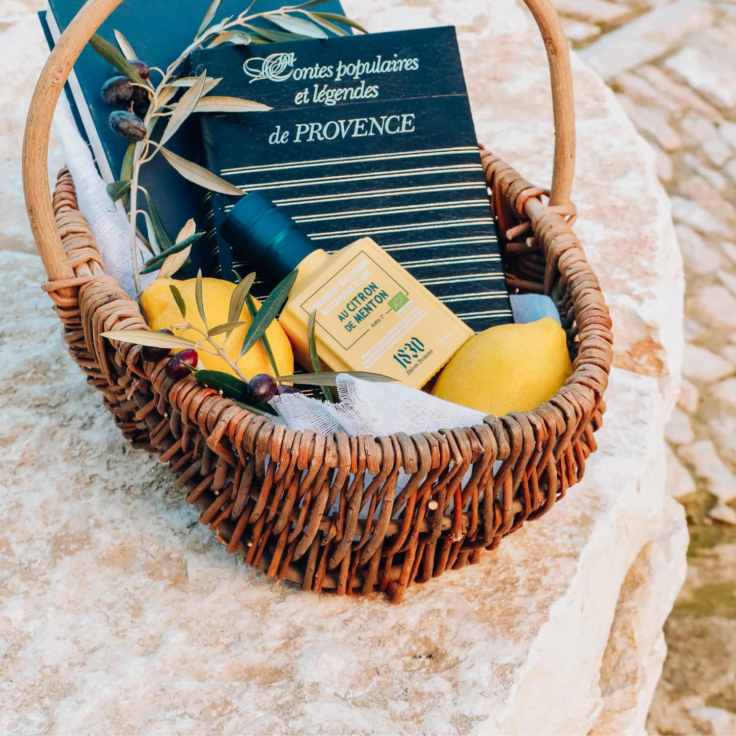 Rustikaler Geschenkkorb mit Maison Brémond 1830 Bio Weißem Balsamico Essig mit Zitrone aus Menton, frischen Zitronen, Olivenzweigen und Büchern über die Provence.