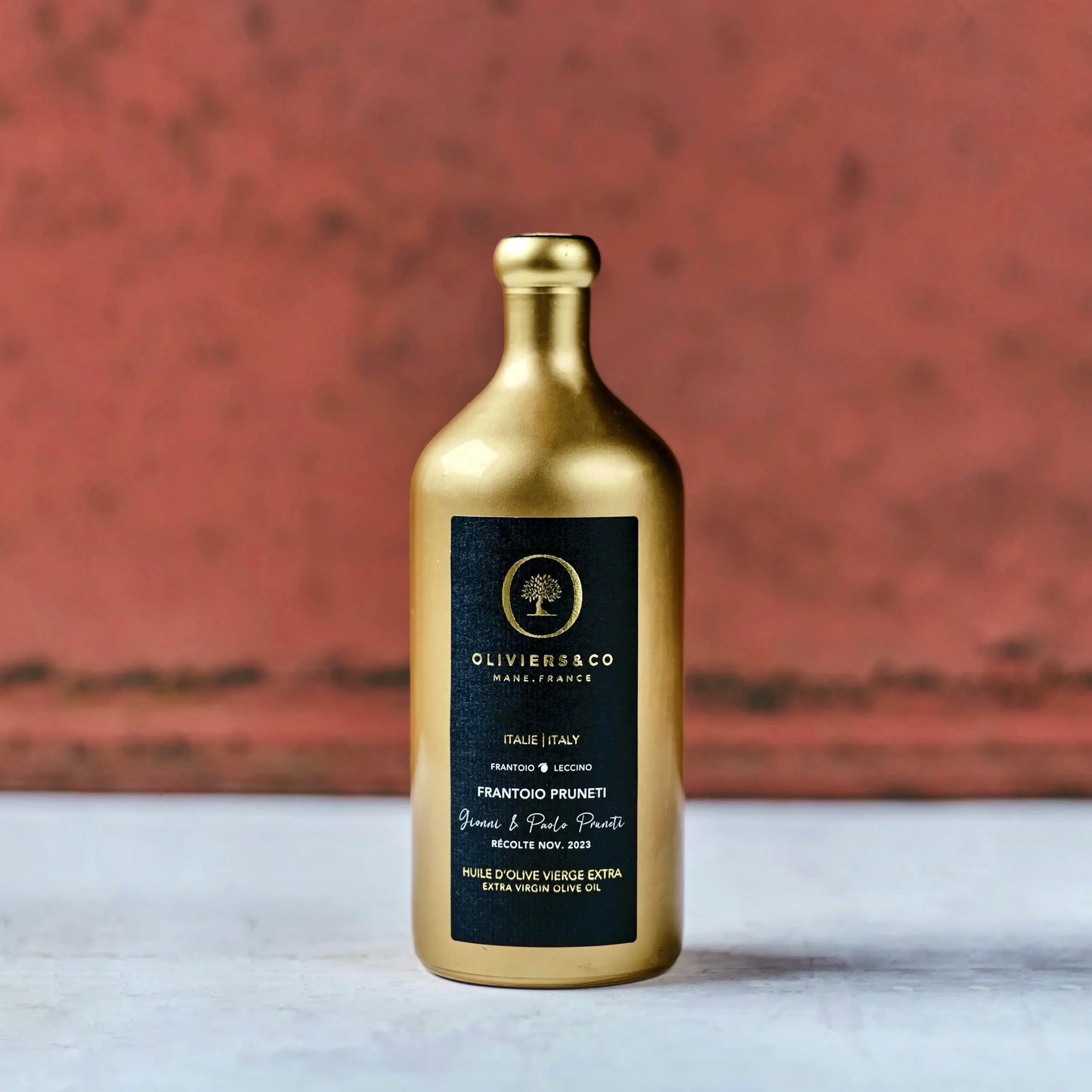Goldene Flasche Olivenöl aus Italien mit schwarzem Etikett der Marke Oliviers & Co. Das Etikett enthält die Aufschrift "Frantoio Pruneti" und "Extra Virgin Olive Oil" sowie Hinweise auf die Herkunft aus der Toskana, Italien, und das Erntedatum im November 2023. Die elegante Verpackung hebt die Hochwertigkeit des Olivenöls hervor.