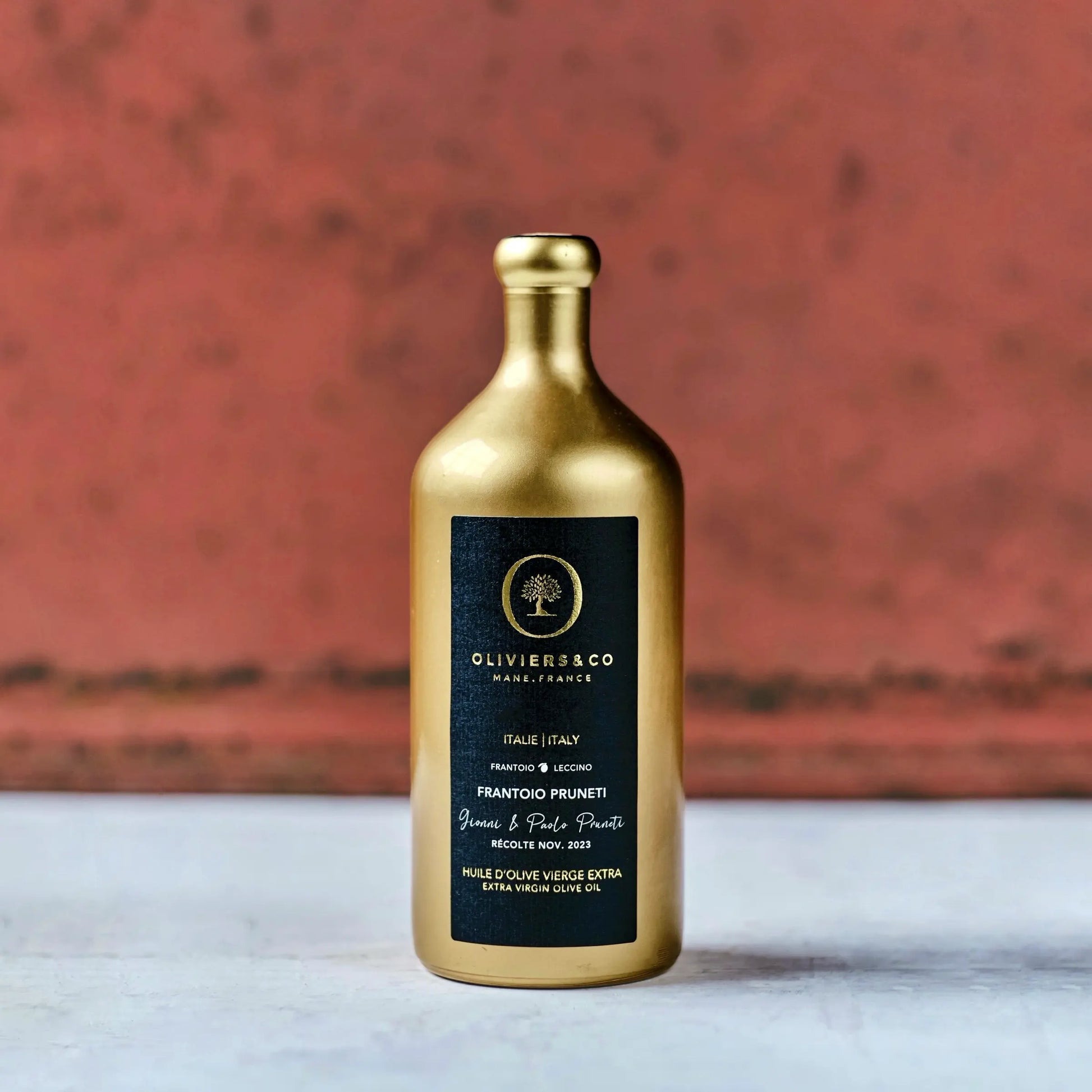 Goldene Flasche Olivenöl aus Italien mit schwarzem Etikett der Marke Oliviers & Co. Das Etikett enthält die Aufschrift "Frantoio Pruneti" und "Extra Virgin Olive Oil" sowie Hinweise auf die Herkunft aus der Toskana, Italien, und das Erntedatum im November 2023. Die elegante Verpackung hebt die Hochwertigkeit des Olivenöls hervor.