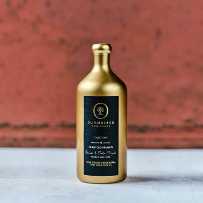 Goldene Flasche Olivenöl aus Italien mit schwarzem Etikett der Marke Oliviers & Co. Das Etikett enthält die Aufschrift "Frantoio Pruneti" und "Extra Virgin Olive Oil" sowie Hinweise auf die Herkunft aus der Toskana, Italien, und das Erntedatum im November 2023. Die elegante Verpackung hebt die Hochwertigkeit des Olivenöls hervor.