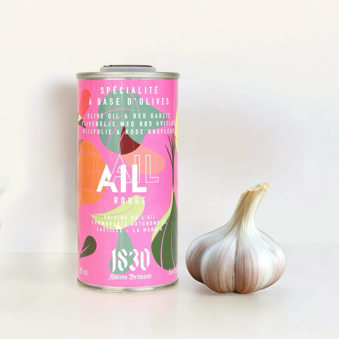 Maison Brémond Knoblauch-Olivenöl 250 ml – Aromatisches Olivenöl mit rotem Knoblauch, präsentiert neben frischen Knoblauchknollen auf hellem Hintergrund.