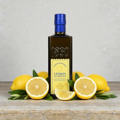 Maison Brémond 1830 Zitronen-Olivenöl aus Menton, umgeben von frischen Zitronen auf rustikalem Holztisch – aromatisches Olivenöl mit natürlichem Zitronenaroma.