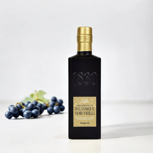 Hochwertiger schwarzer Balsamico-Essig – 20 Jahre gereift, präsentiert mit frischen Weintrauben auf weißem Hintergrund – ein Zeichen für höchste Qualität.
