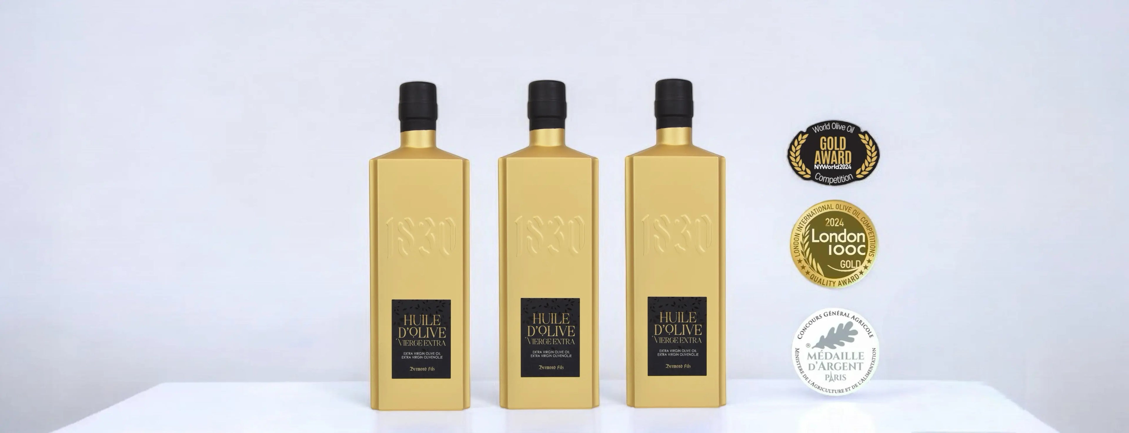 Drei goldene Flaschen von Maison Brémond 1830, ausgezeichnet als Testsieger Olivenöl im Olivenöl Test, mit hochwertigen Goldmedaillen wie der London International Olive Oil Competition und der Médaille d'Argent. Ein Premiumprodukt für Feinschmecker, die erstklassiges Olivenöl kaufen möchten.