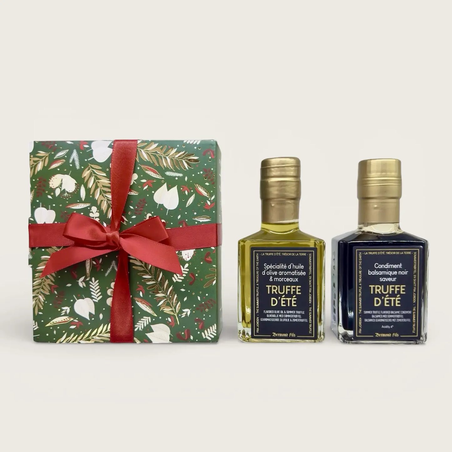 Feinkost-Geschenkset mit Olivenöl mit Sommertrüffel und schwarzem Balsamico mit Sommertrüffel neben dekorativer Geschenkbox mit roter Schleife