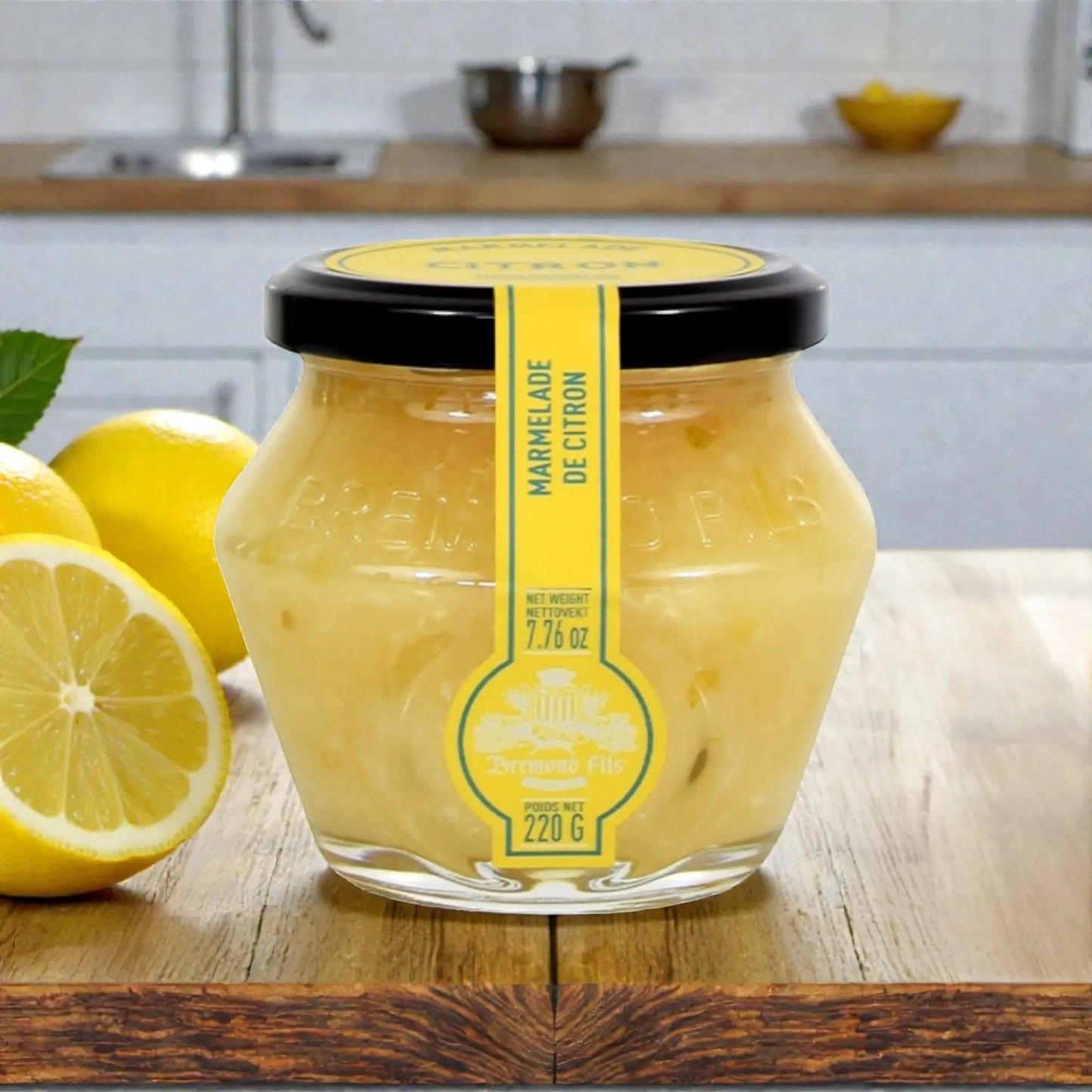 Handgemachte italienische Zitronenmarmelade im Glas mit frischen Zitronen, auf Holztisch in Küche
